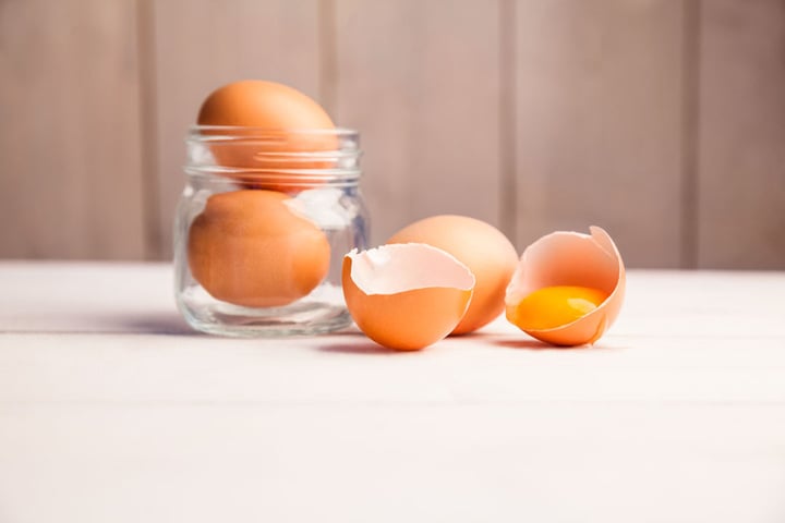 eggs in a jar by broken egg shells on the table