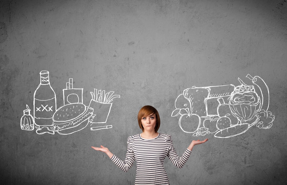 young woman choosing between healthy and unhealthy foods