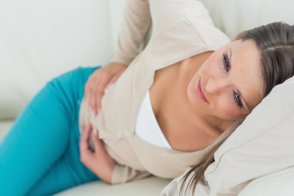 Woman lying on sofa with in pain with digestive issues