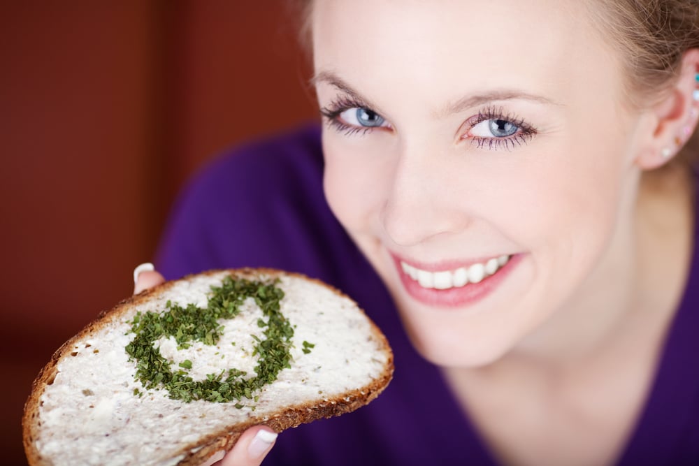 Woman eating bread with cheese and a heart of herbs